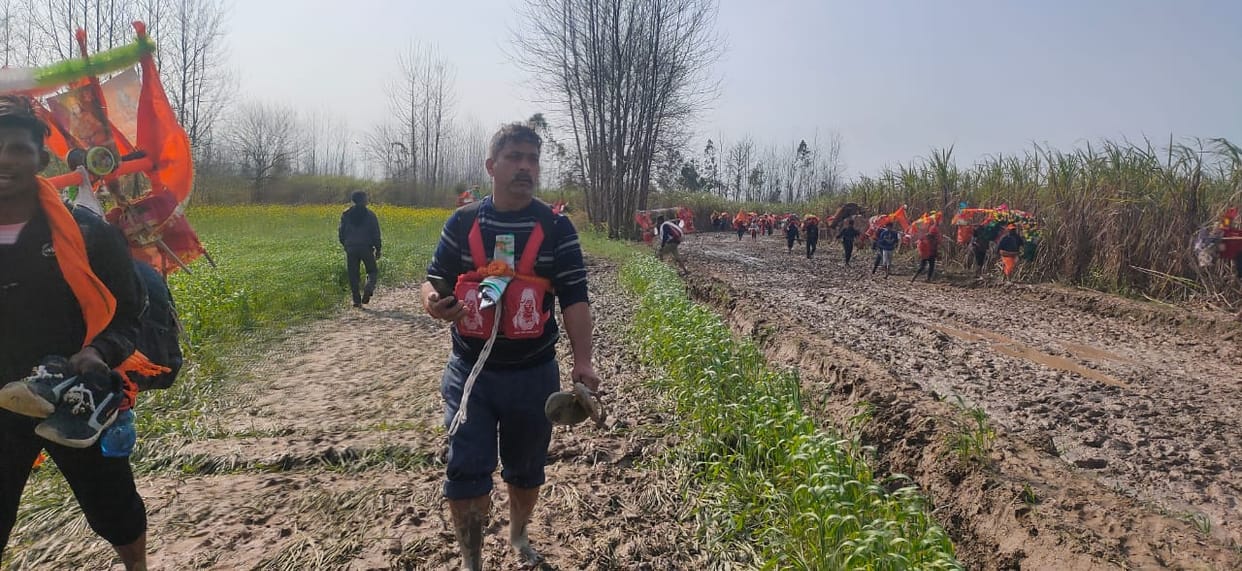 Kanwariyas passing through the mud by picking up shoes and slippers