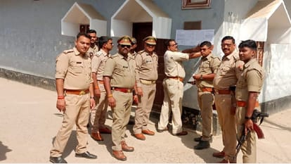 घर पर नोटिस चस्पा करती पुलिस।