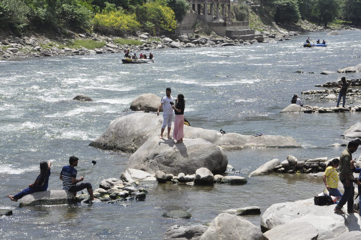 Tourists descending into the Beas river with their lives on their palms