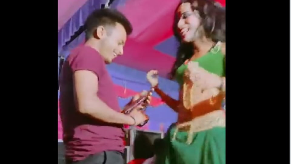 man holding a gun in his hand while dancing with a female dancer in Bihar’s Gopalganj