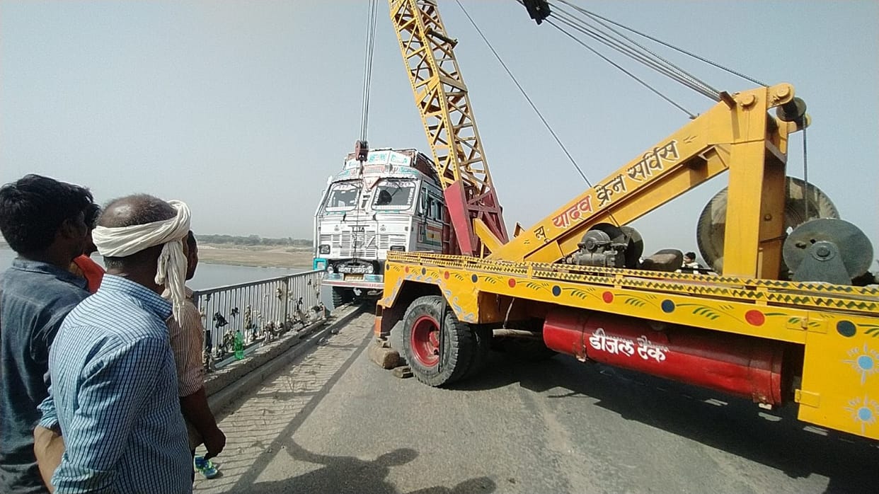 Truck hanging on the bridge by breaking the railing, jammed