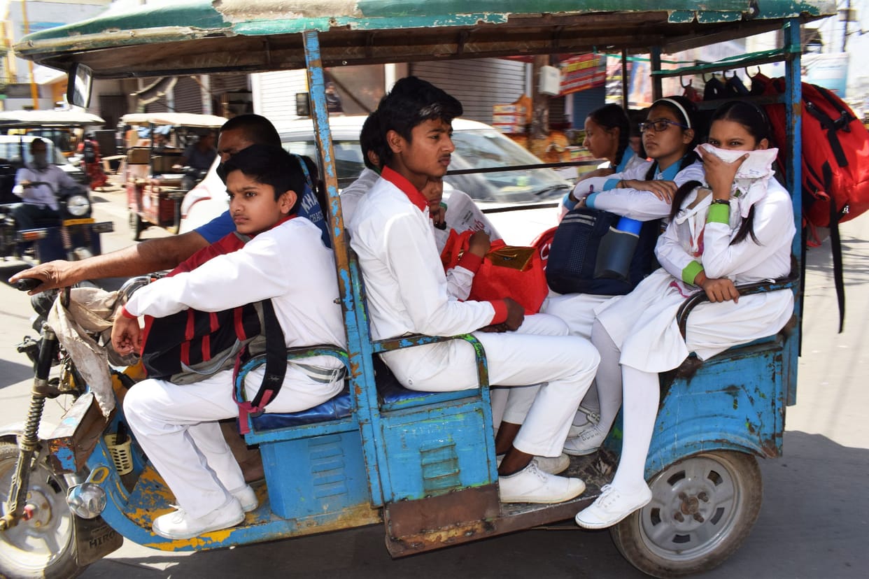 School children sitting on driver's seat in e-rickshaw