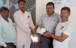परौंख में किसान को फसल नुकसान मुआवजे की चेक देते तहसीलदार व कानूनगो। संवाद