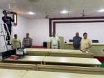 केएनआई के सभागार मे प्रोजेक्टर लगाता कर्मी।