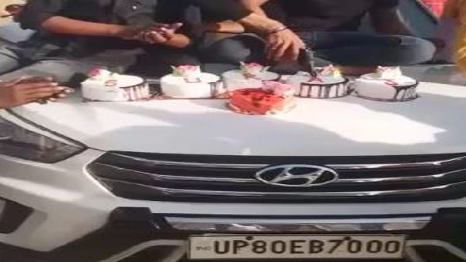 young man cut cake with pistol on bonnet of car in Firozabad