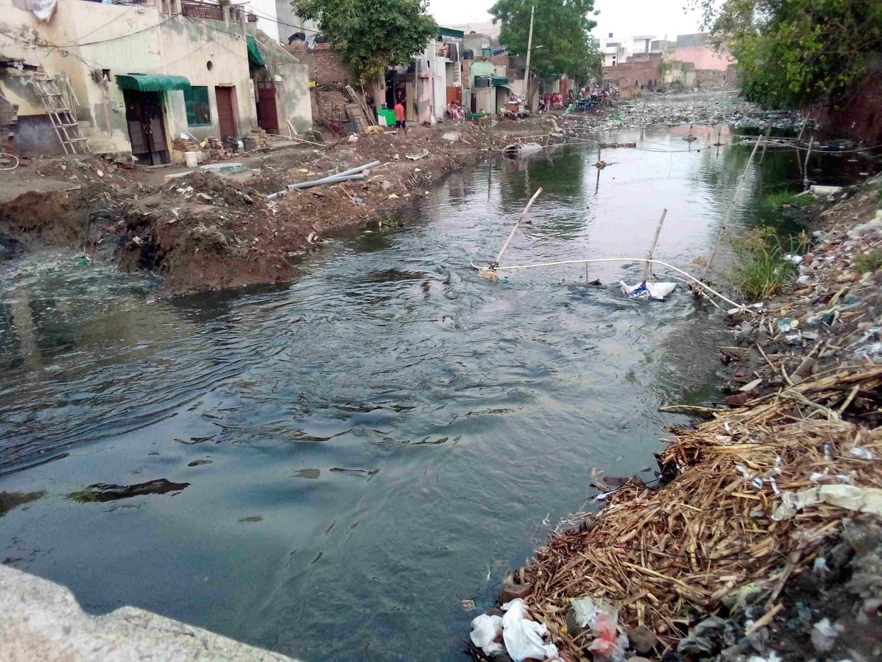 The contaminated water of the overflow drain filled the bus stand, passing through it, the passengers had to catch the bus.