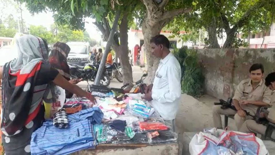 man sells clothes by handcart under the police protection in etah