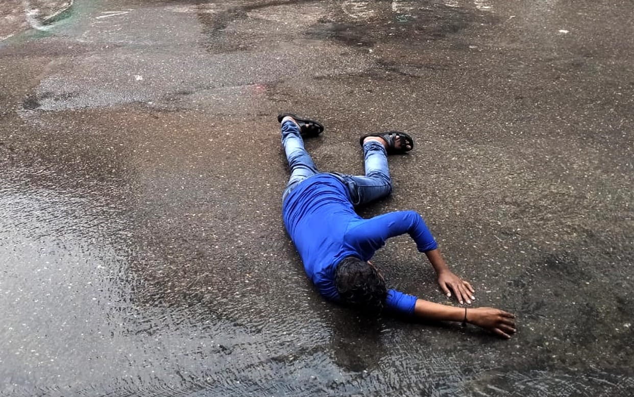 Drunk man lying on the road in the middle of the rain