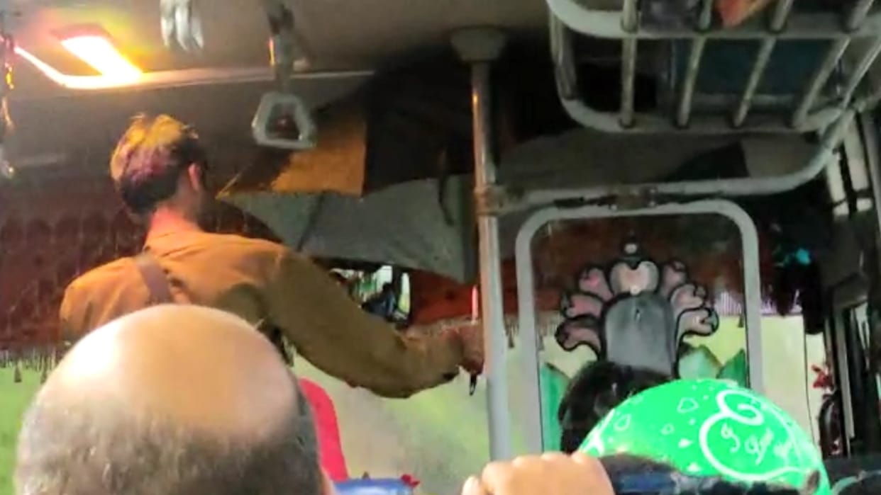The driver had to open the umbrella to avoid the water dripping inside the bus, then the pole opened