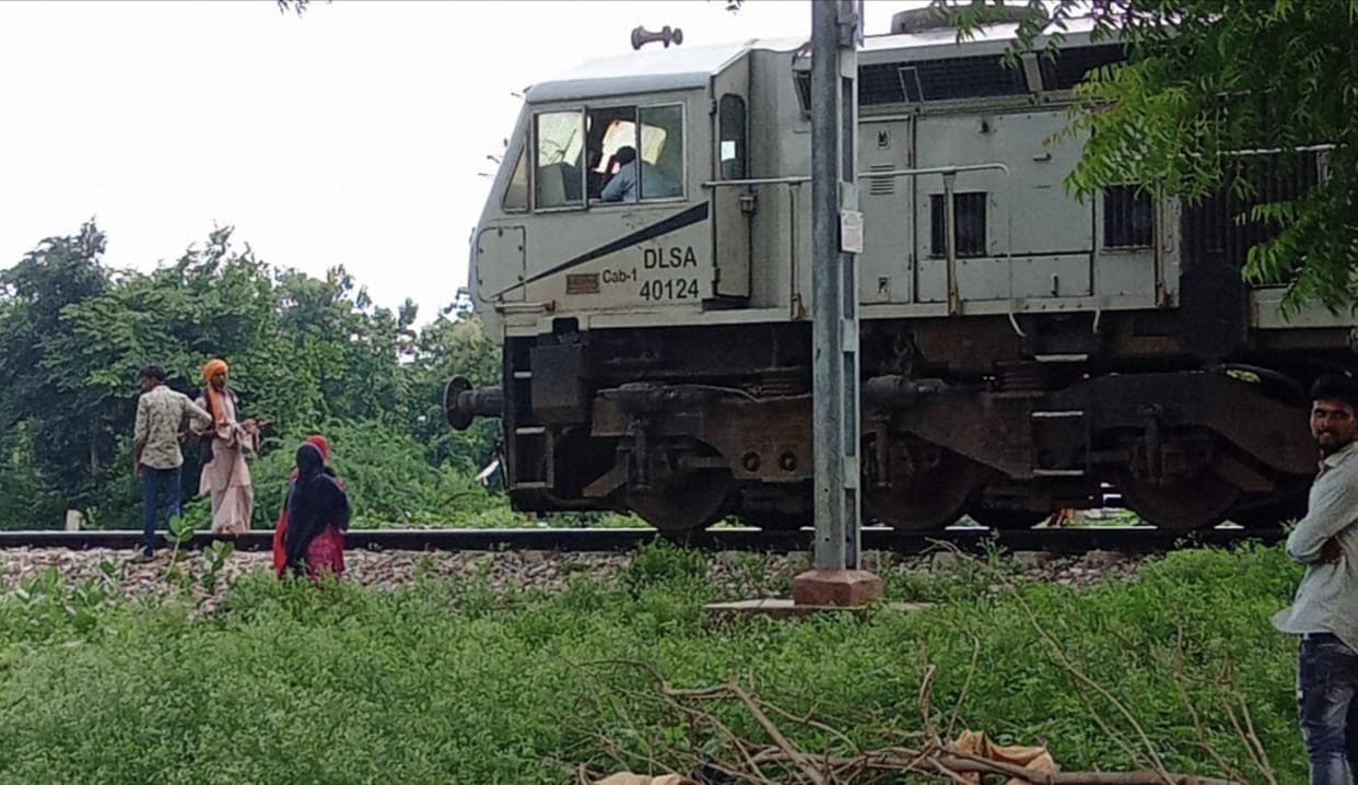 a young man was standing in front of the train with Baby in his lap in Unnao
