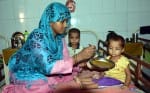 पोषण पुर्नवास केन्द्र में बच्चें को पोष्टिक आहर देती महिला।।