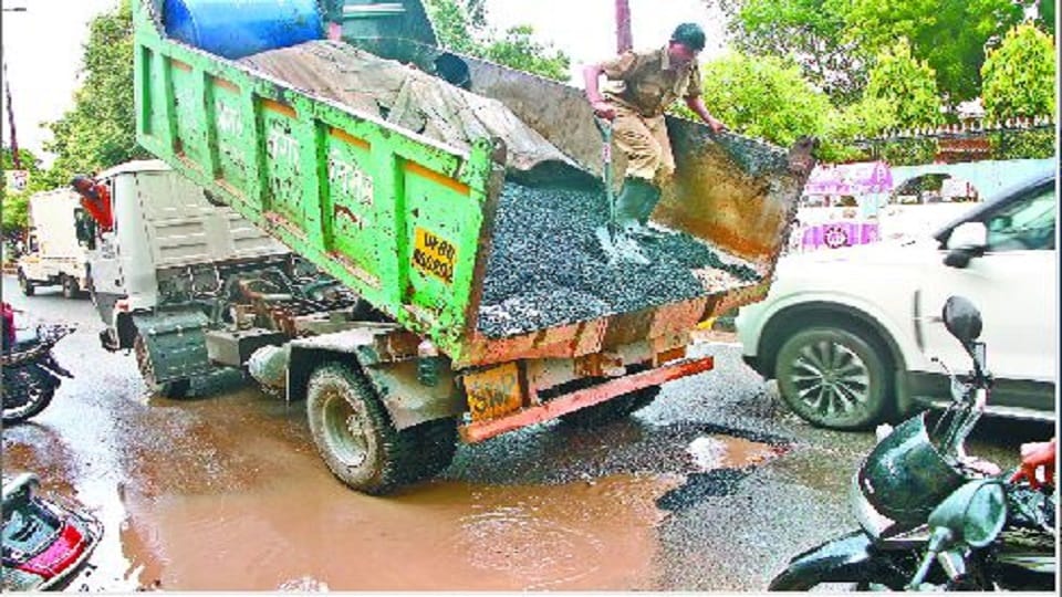 Asphalt-ballast laid to build a road in water filled with potholes due to rain in agra