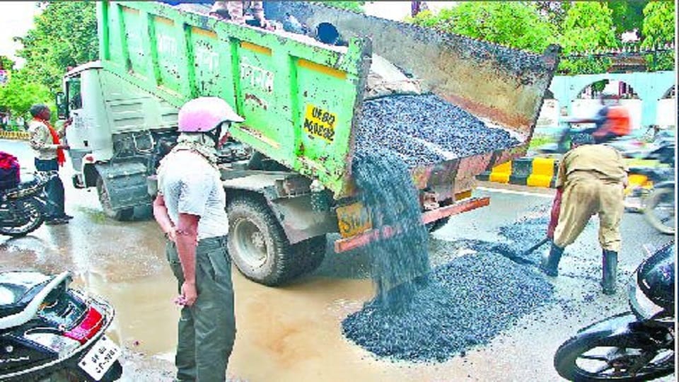 Asphalt-ballast laid to build a road in water filled with potholes due to rain in agra