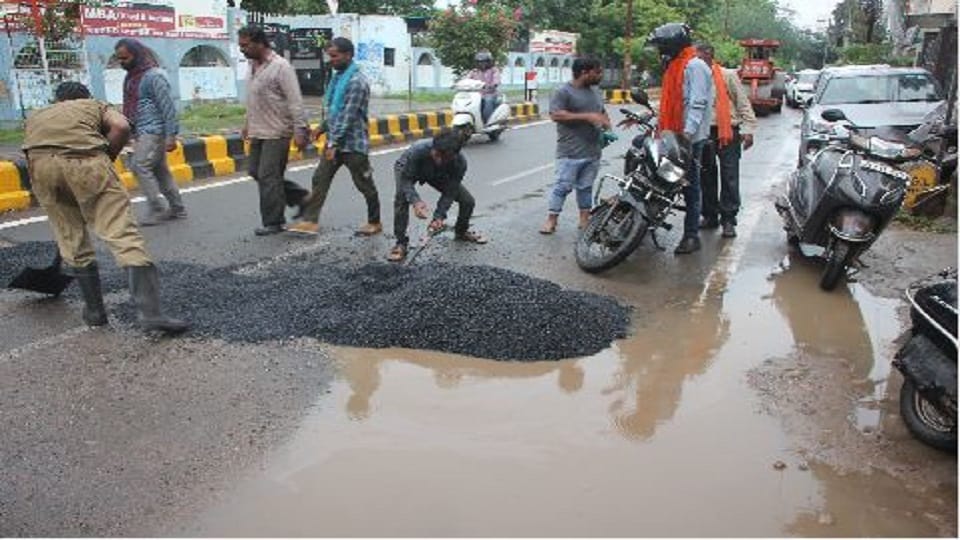 Asphalt-ballast laid to build a road in water filled with potholes due to rain in agra