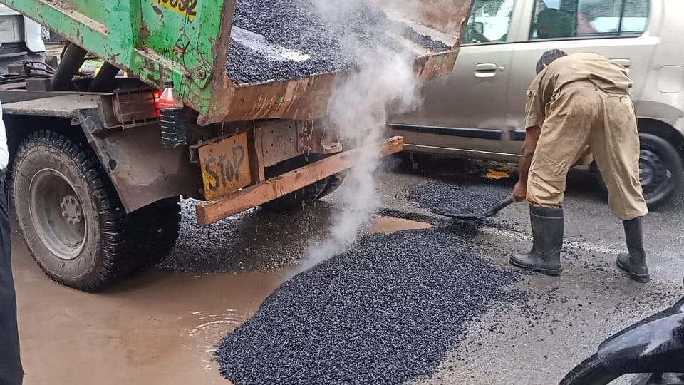 Asphalt-ballast laid to build a road in water filled with potholes due to rain in agra