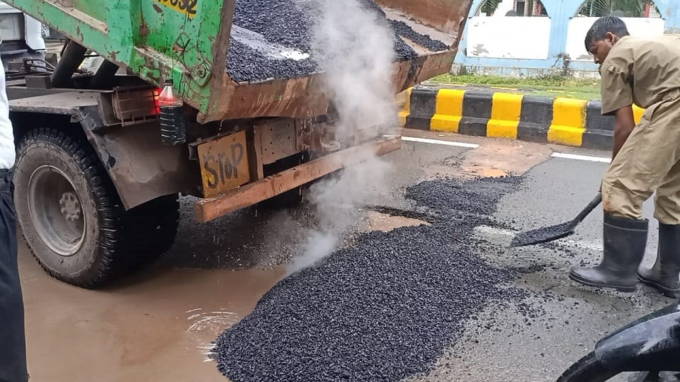 Asphalt-ballast laid to build a road in water filled with potholes due to rain in agra