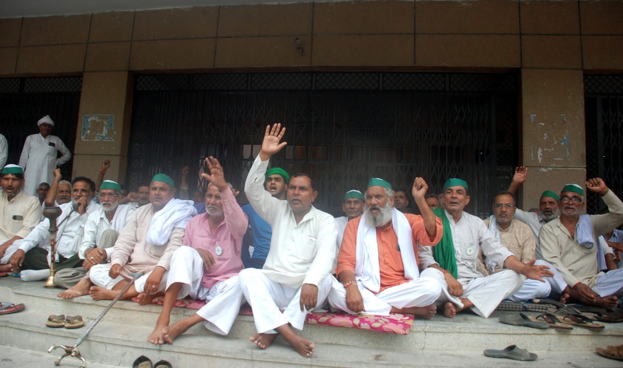 Farmers sitting on dharna in rain, embroidery mounted in collectorate