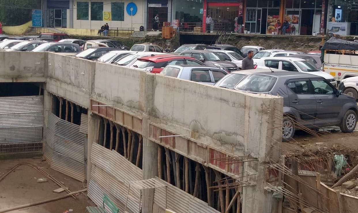 Vehicles being parked on the lenter of under construction parking lot in Kullu