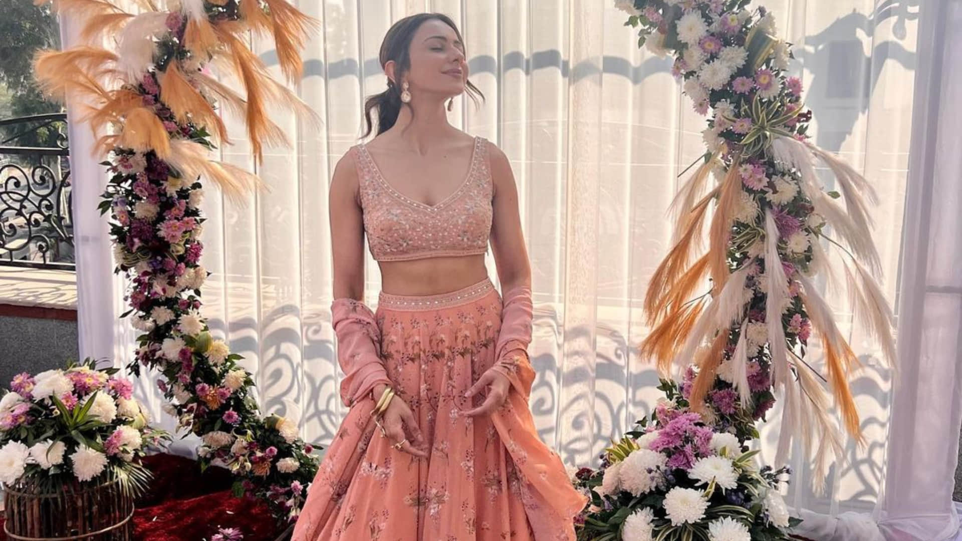 rakul preet singh poses in sunkissed light at wedding wearing peach printed lehenga