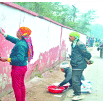 फतेहाबाद रोड पर बाउंड्री वॉल की रंगाई-पुताई करते मजदूर