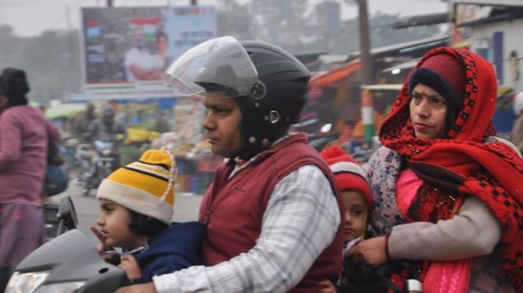 वाराणसी में भीषण ठंड के बीच एक स्कूटी पर सवार परिवार