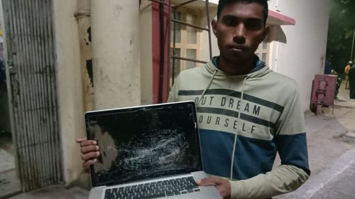 क्षतिग्रस्त लैपटॉप के साथ खड़ा छात्र