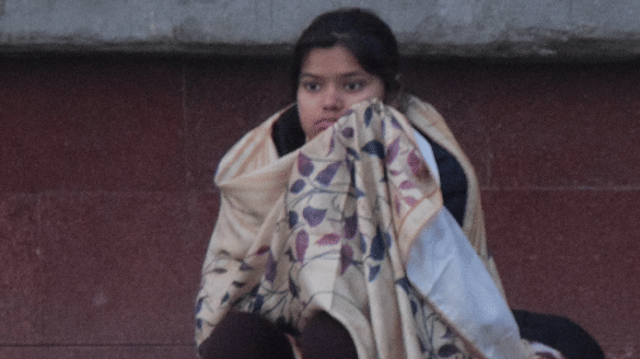 ठंड में शॉल ओढ़कर ट्रेन का इंतजार करती किशोरी