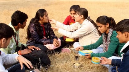 काशी विद्यापीठ परिसर में धूप का आनंद लेते छात्र-छात्राएं