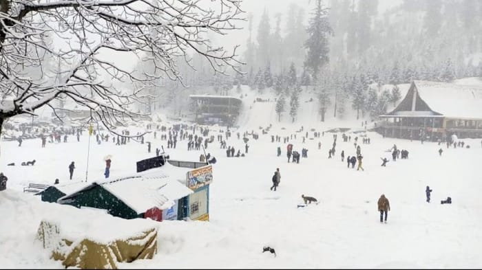 बर्फबारी के बीच सैलानी।