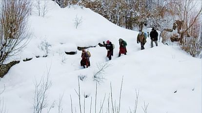 लाहौल-स्पीति के राशेल गांव में बर्फबारी के बीच पैदल चलकर पीठ पर पीने का पानी ले जाते ग्रामीण।