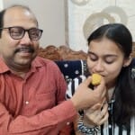 मनस्वी श्रीवास्तव को मिठाई खिलाते पिता मुकेश श्रीवास्तव
