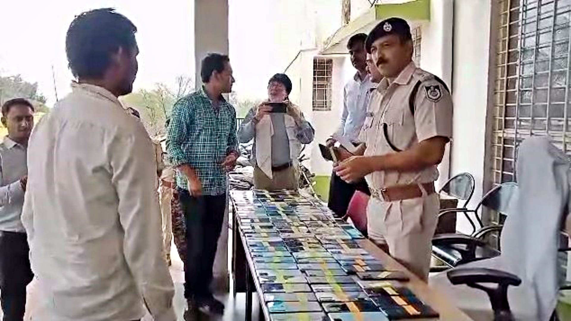 युवक को मोबाइल फोन लौटते एसपी