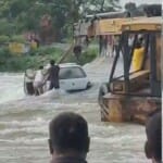 कार को पानी से निकालती क्रेन।