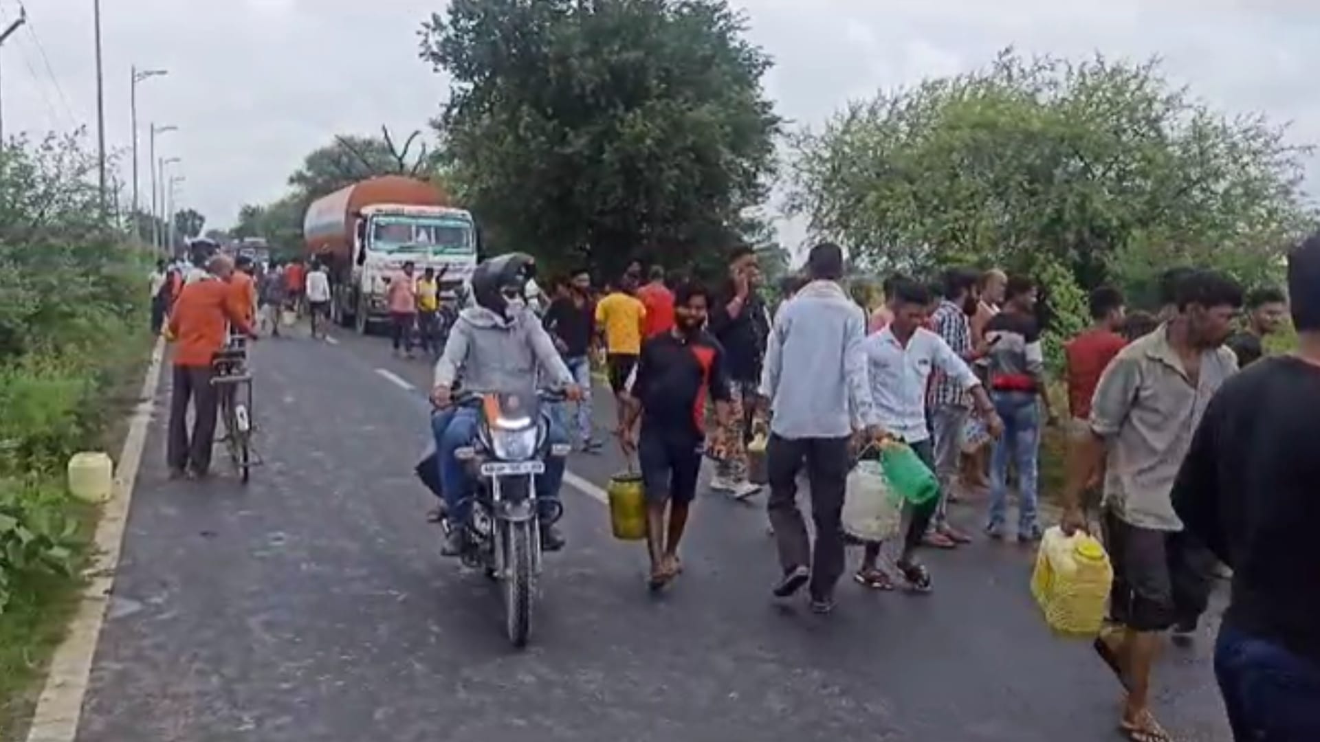 डिब्बों में तेल भरकर ले जाते लोग