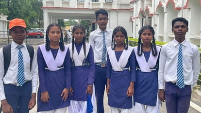 Students study after first sweeping the school in Korba