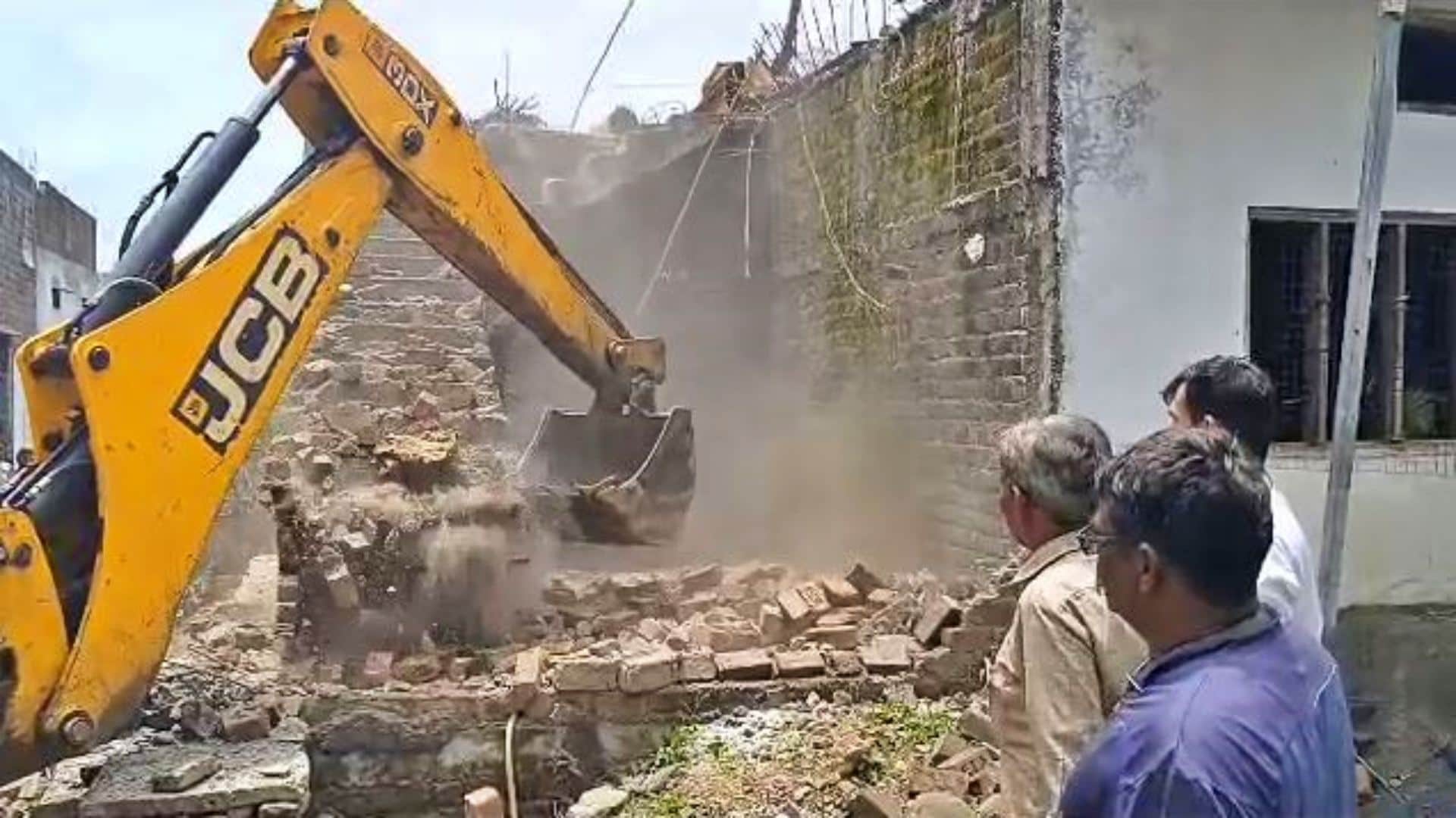 अवैध निर्माण गिराता बुलडोजर।