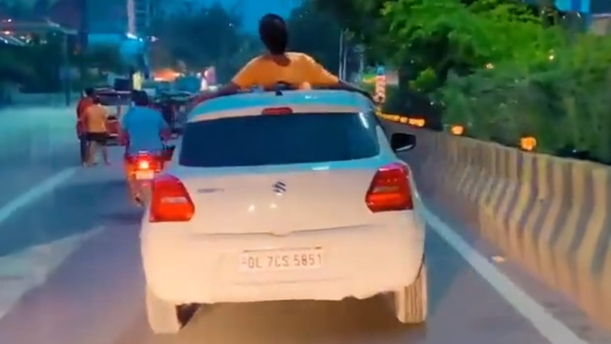 Stunt performed by lying on roof of car Video viral incident noida police challaned Rs 26,000