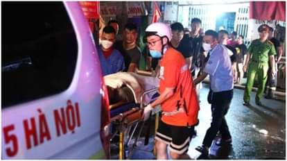 हनोई के एक अपार्टमेंट में भीषण आग लगने के बाद पीड़ितों को एंबुलेंस में ले जाते बचावकर्मी।