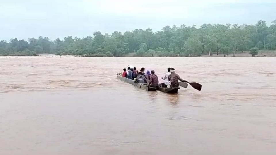 नाव से उफनती नदी पार करते ग्रामीण