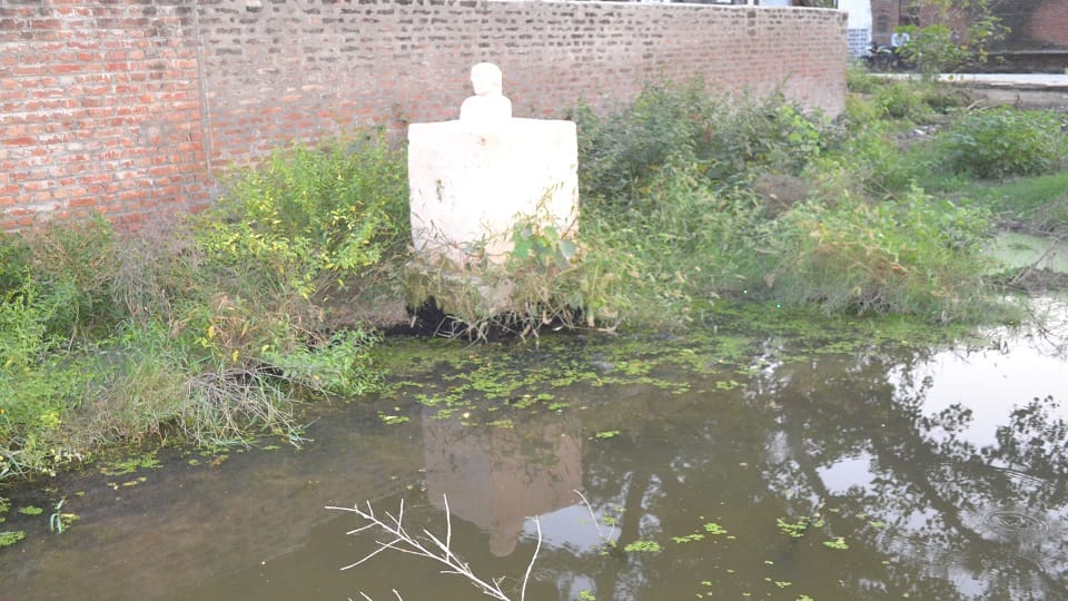Gandhi statue standing in the middle of dirty water