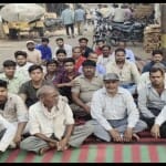 Firozabad: काठ बाजार में धरने पर बैठे पीड़ित दुकानदार।
