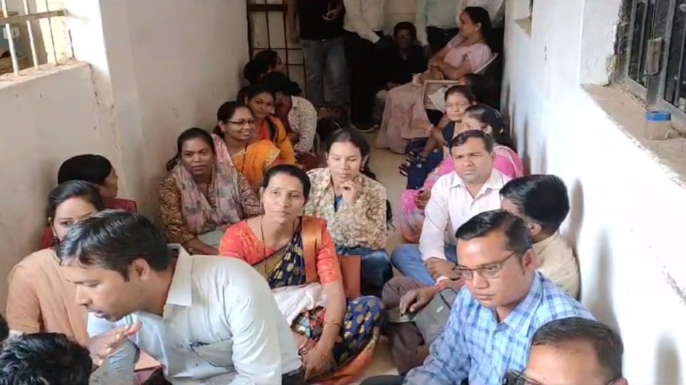 Teachers sitting on the ground in front of the District Education Officer office demanding posting