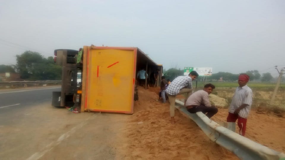 Truck full of sand collides with divider and overturns