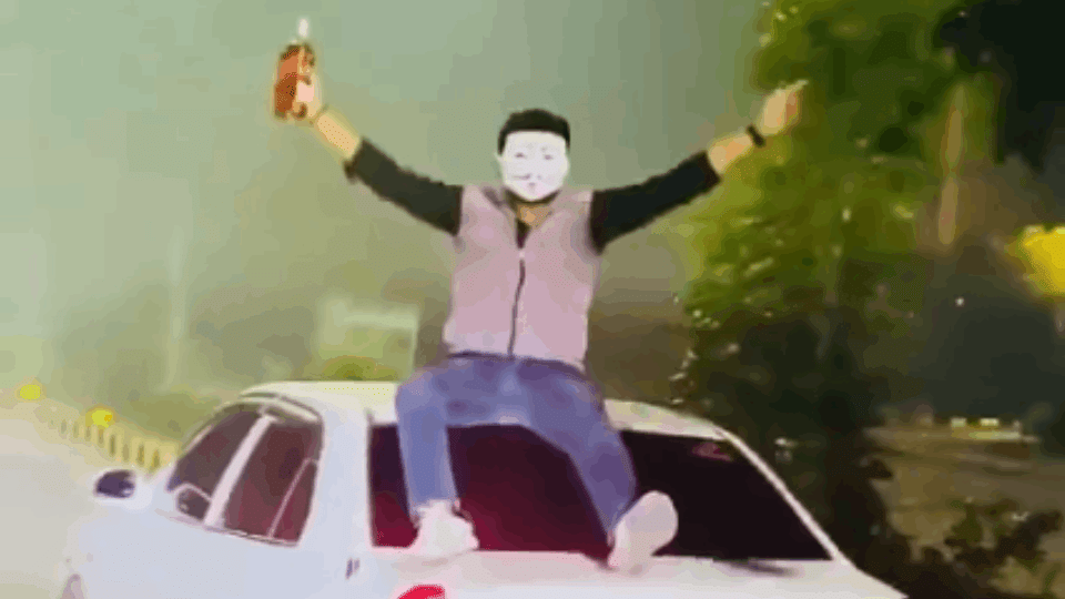 Liquor bottle waved on the roof of a moving car