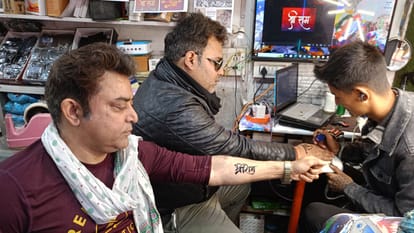 सिगरा स्थित एक टैटू शॉप पर रामनाम का टैटू बनवाते युवा