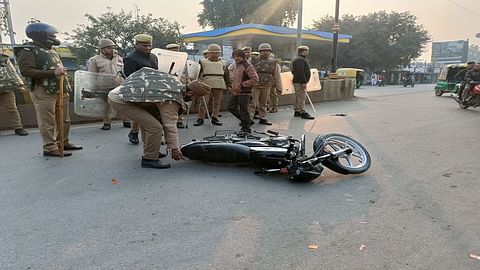 सड़क पर पड़ी बाइक उठाती पुलिसकर्मी