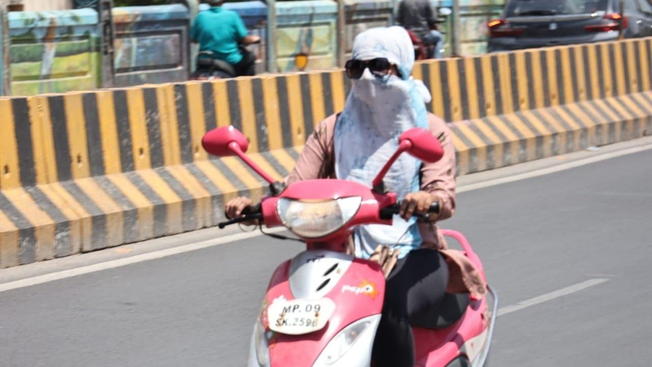 इंदौर में धूप से बचने के लिए दुपट्टे से खुद को ढंके एक युवती। फोटो- जयेश मालवीय।