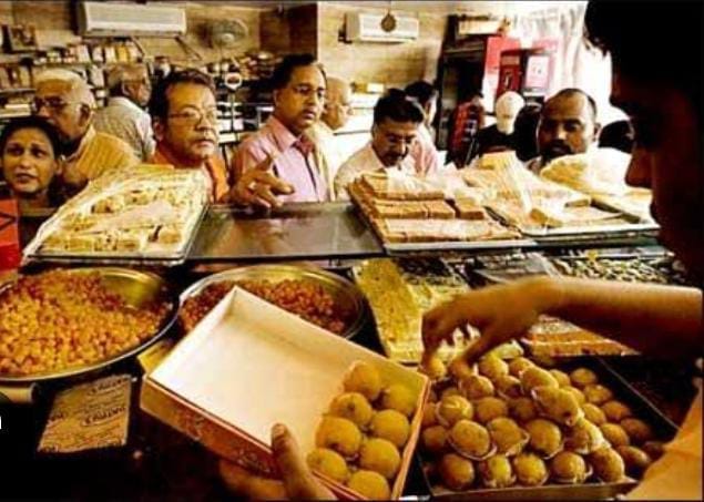 Shopkeepers weighing boxes along with sweets
