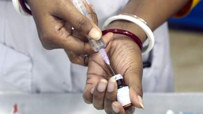 A health worker fills a syringe with measles Vaccine
