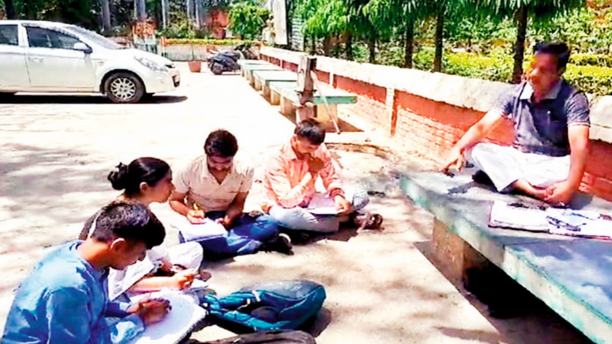 teachers teaching students sitting on the ground under a tree in Meerut College